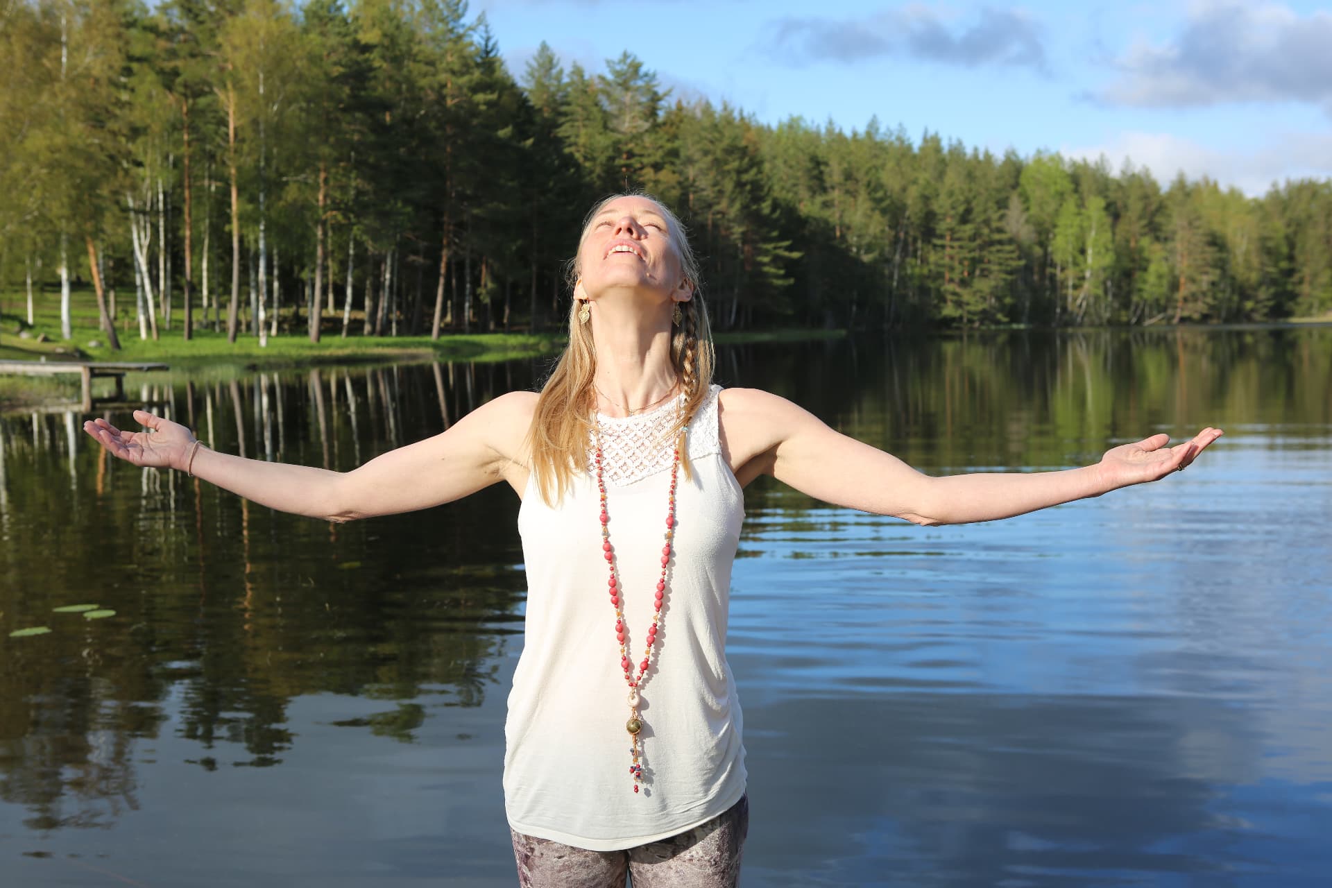 Sanna med armarna öppna mot himlen vid en sjö